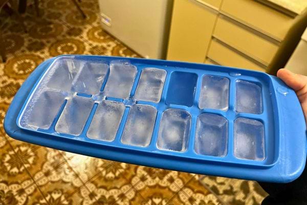 Bac à glaçons bleu rempli de glaçons partiellement formés.