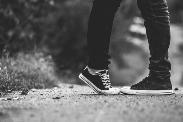 Deux personnes s’embrassent, vues seulement par leurs pieds.