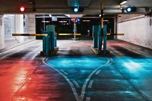 Entrée de parking souterrain avec barrières et lumières rouge et bleue.