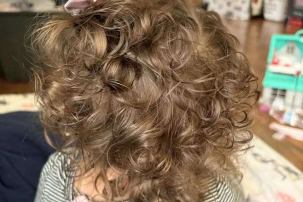 Enfant aux cheveux très bouclés et emmêlés.