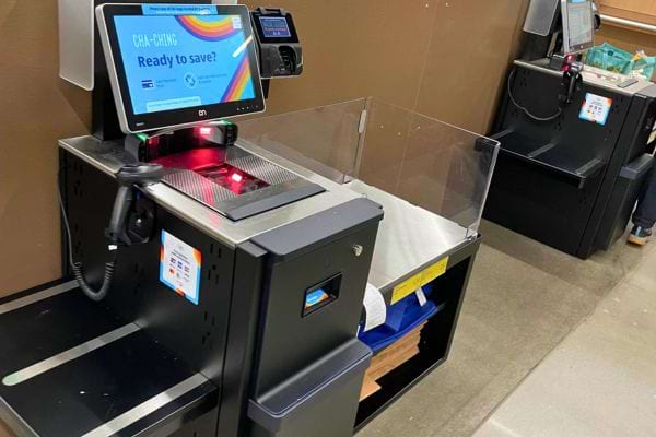 Caisse automatique moderne avec écran coloré et balance vide.