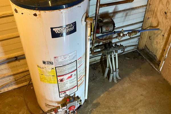 Vieux chauffe-eau Whirlpool rouillé dans un garage.