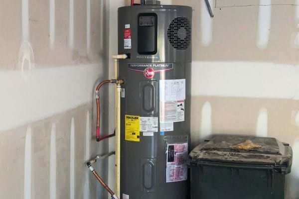 Chauffe-eau intelligent gris foncé près d’une poubelle.