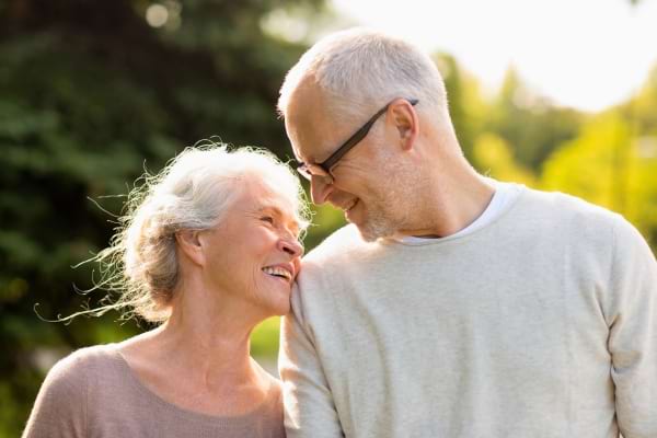 Un couple de seniors complices et souriants en plein air.