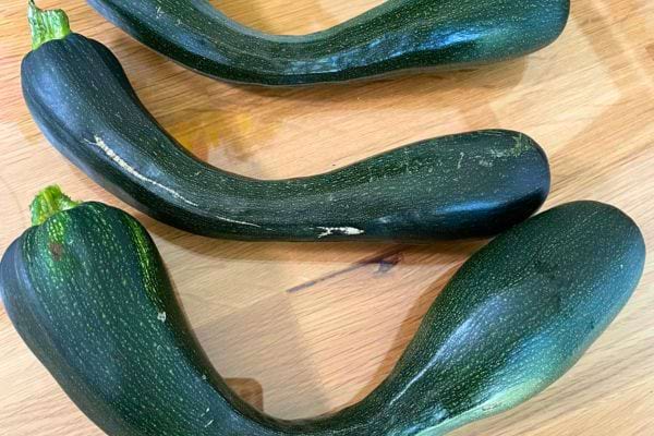 Courgettes vertes difformes sur une table.