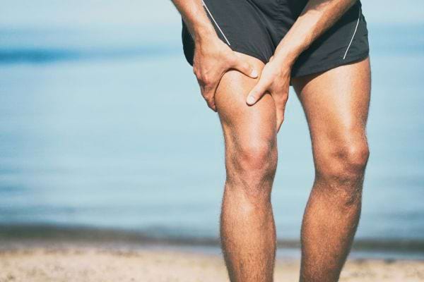 Homme tenant sa cuisse, probablement à cause d'une crampe.