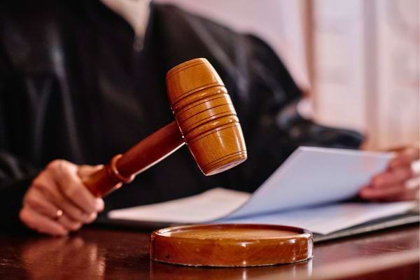 Juge tenant un maillet au-dessus d’un bureau.