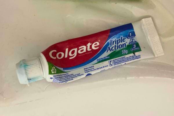 Tube de dentifrice Colgate Triple Action sur un lavabo.
