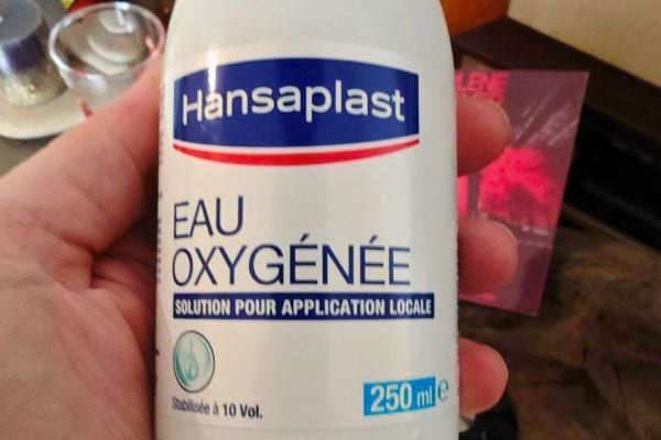 Flacon d’eau oxygénée en main