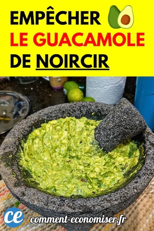 Un guacamole dans un mortier en pierre avec un pilon, entouré de citrons verts.