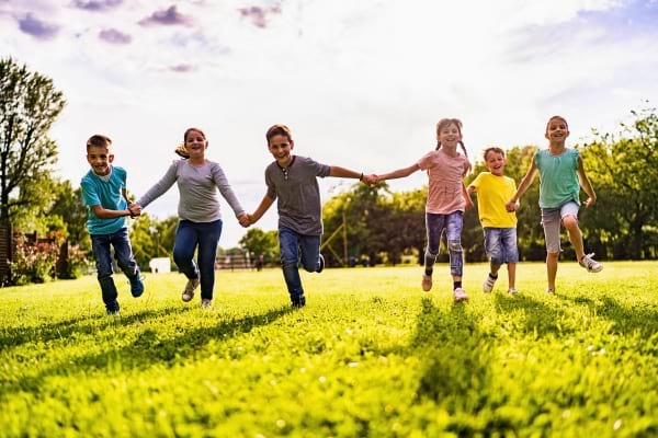 Des enfants courent et jouent joyeusement dans un parc verdoyant.