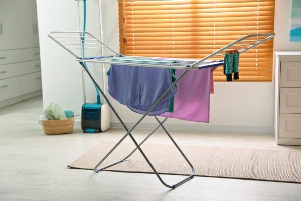Étendoir avec vêtements dans une pièce lumineuse.
