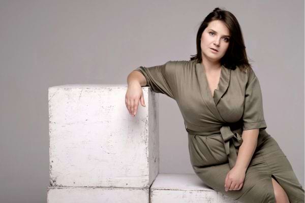 Femme aux formes généreuses assise sur un cube.