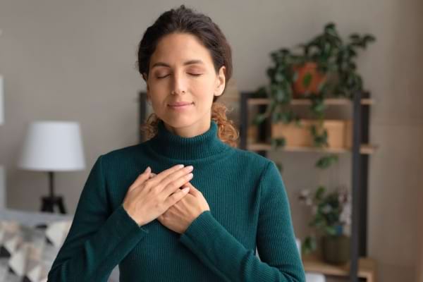 Femme sereine, main sur le cœur.