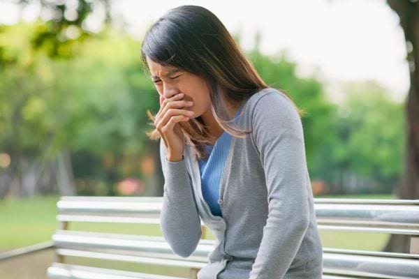 Femme assise toussant et se sentant mal.