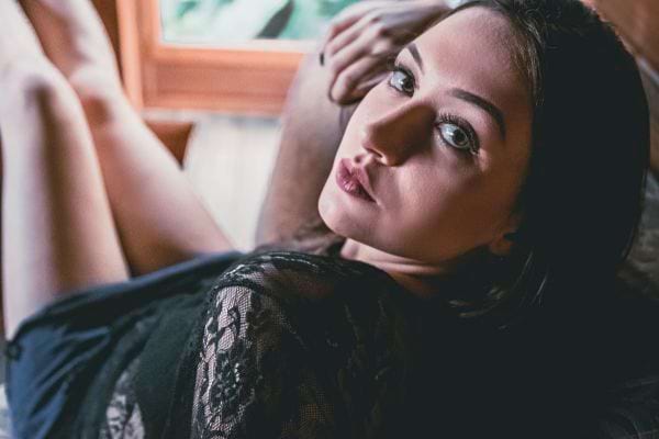 Femme en lingerie noire allongée, regard intense.