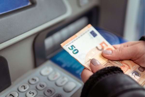 Une femme tient deux billets juste après un retrait.