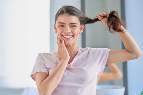Femme souriante avec de beaux cheveux en main.