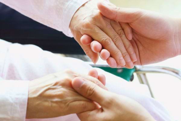 Une main chaleureuse enveloppe celle d'une personne affaiblie.