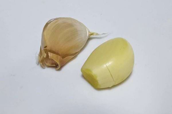Gousse d’ail avant et après épluchage sur fond blanc.