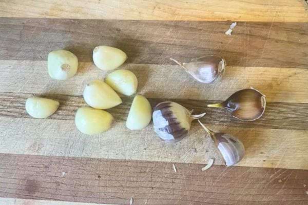 Gousses d’ail épluchées posées sur une planche en bois.