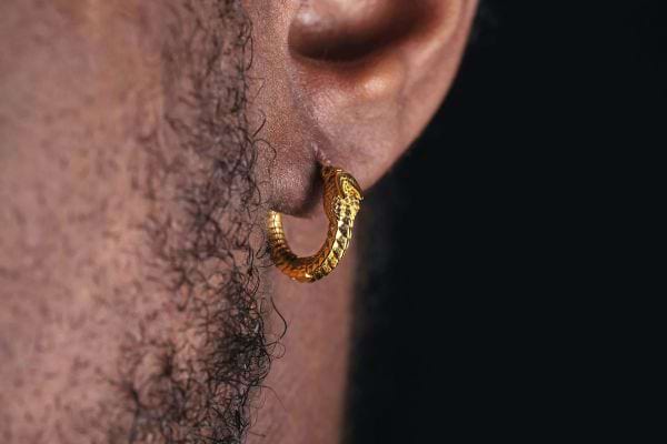 Boucle dorée en forme de serpent à l’oreille.