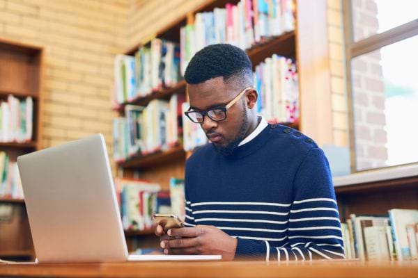 Un homme consulte son téléphone en silence à la bibliothèque.