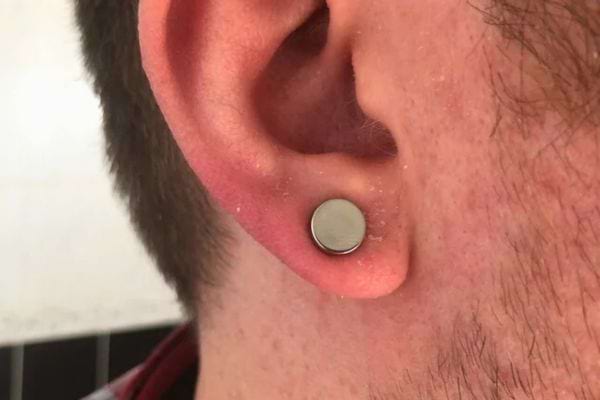 Homme portant une petite puce métallique.