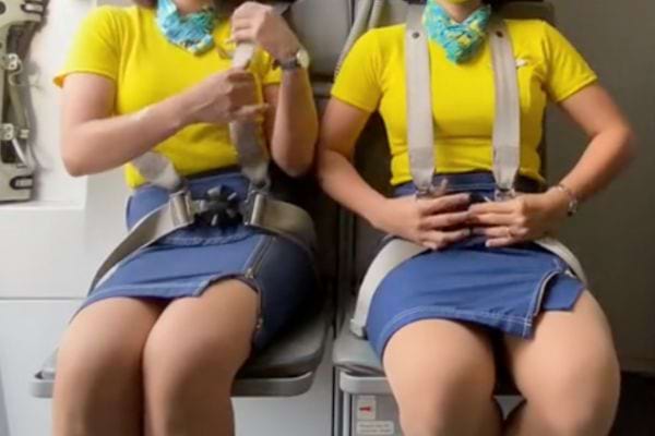 Les deux h&ocirc;tesses ajustent ou v&eacute;rifient leur ceinture de s&eacute;curit&eacute;.