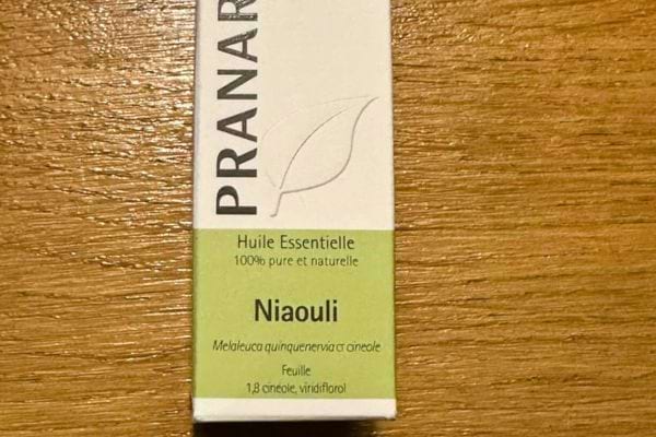 Boîte d’huile essentielle de niaouli posée sur une table.