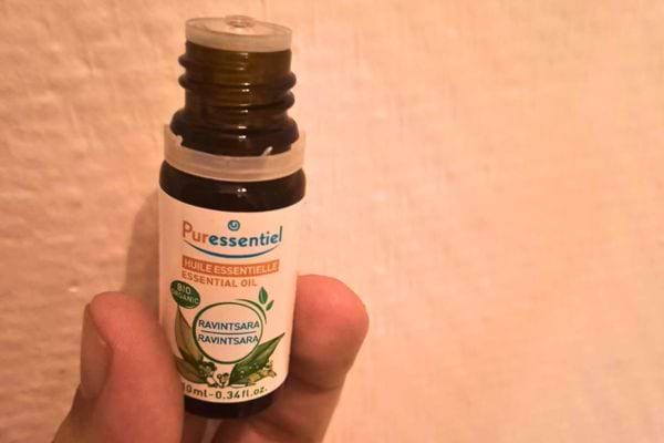 Flacon d’huile essentielle de ravintsara tenu à la main.