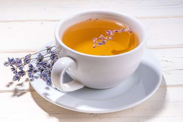 Tasse d’infusion à la lavande avec fleurs séchées flottantes.