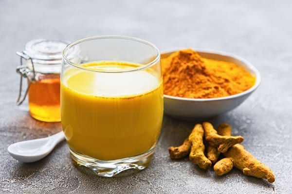 Lait doré au curcuma, accompagné de miel et racines de curcuma.