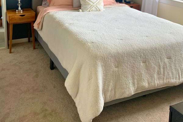 Lit bien fait avec une couette blanche.