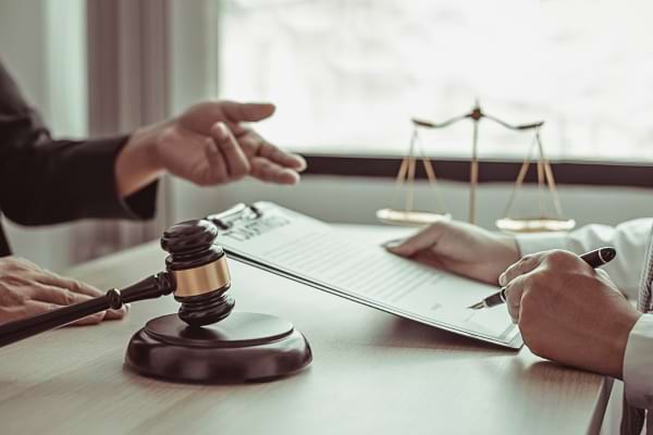 Deux personnes discutent d’un document juridique près d’un maillet de juge.