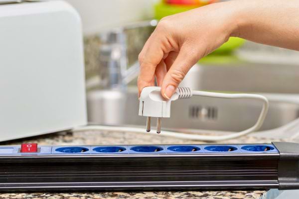 Une main branche un câble sur une multiprise.