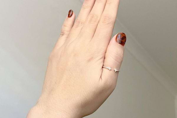Main levée avec bague fine en forme d’étoiles au pouce.