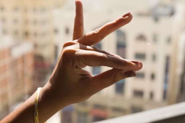 Main en mudra avec une ville floue en arrière-plan.