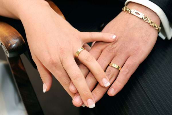 Mains croisées avec alliances en or lors d’un mariage.