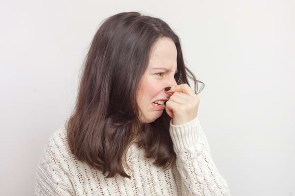 Femme gênée par une mauvaise odeur qu’elle sent avec dégoût.