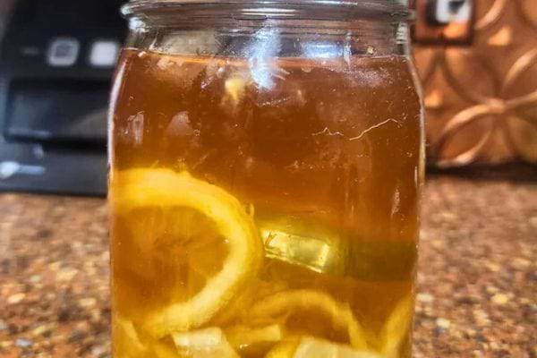 Bocal de miel citron maison sur plan de travail.