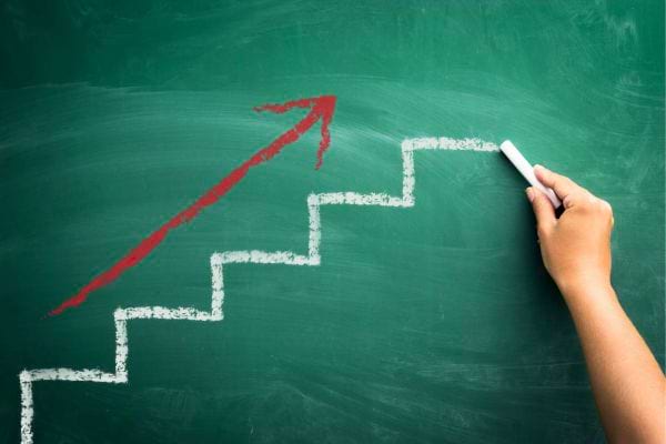 Main dessinant des marches avec flèche vers le haut.