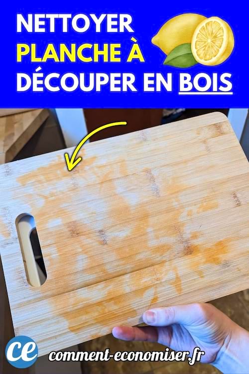 Planche à découper en bois tachée tenue par une main dans une cuisine.