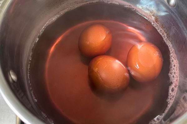 Œufs cuisant dans une eau foncée