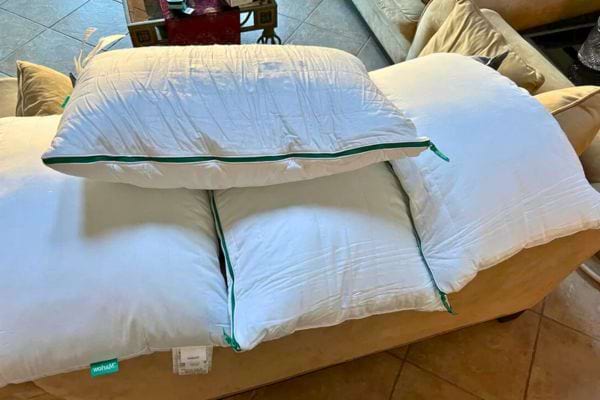 Oreillers blancs alignés sur un canapé.