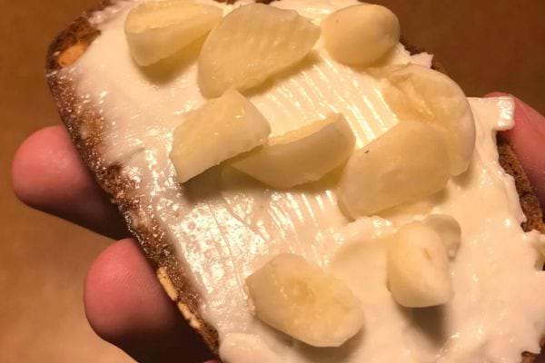 Tartine de fromage frais avec morceaux d’ail cru.