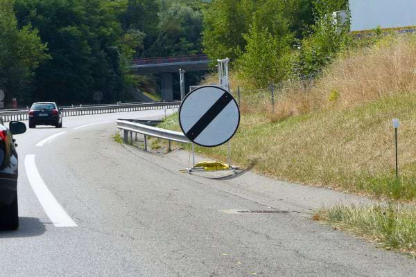 Panneau temporaire de fin de limitation posé sur accotement routier.