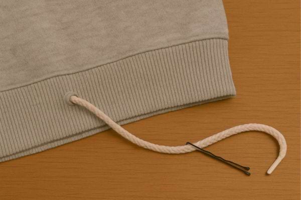 Épingle glissée dans un cordon de sweat-shirt.