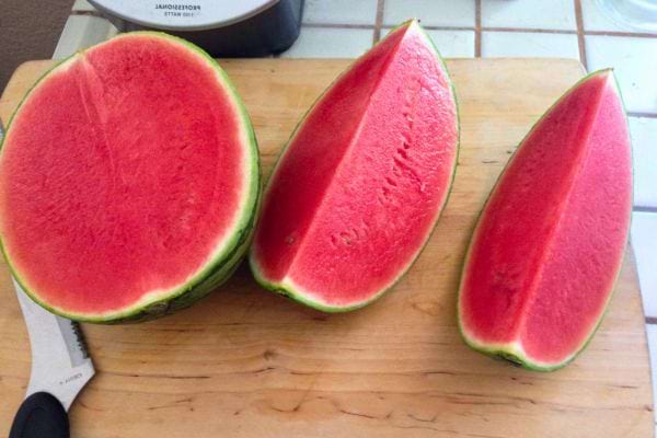Pastèque coupée en tranches sur une planche.