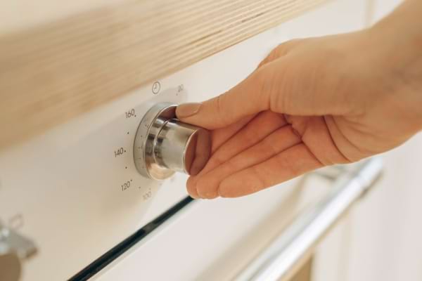 Main réglant la température d’un four.
